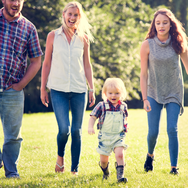 young family walking in grass, mom, dad, toddler boy, teenage girl